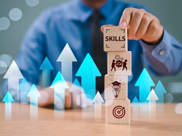 A person stacks blocks with icons for skills, collaboration, ideas, and targets.
