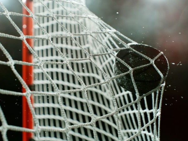 A hockey puck hits the back of a net