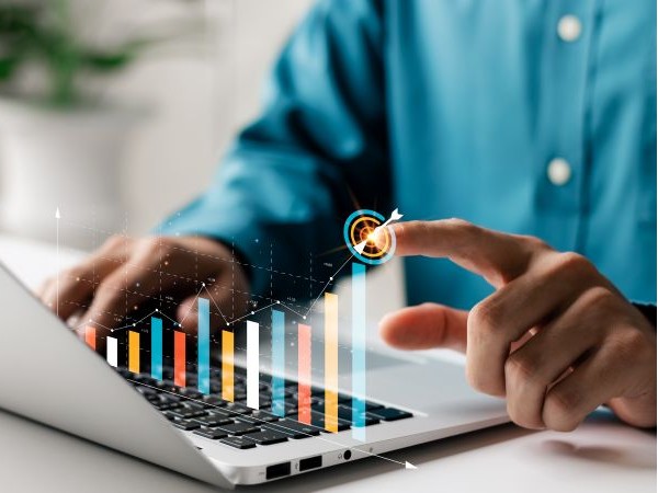 A person taps a target on a colorful bar graph image overlaid on a laptop keyboard