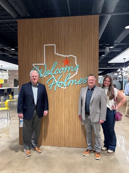 Tim Anders, Kyle Coughlin, and Bailey Lamm of Innovative Program Solutions pose with a Welcome Holmes sign at the Holmes Murphy Dallas office.