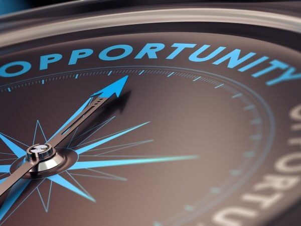 A close up of a compass with a blue arrow pointing toward the word opportunity