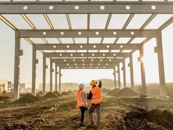 Two construction workers looking out on the foundation of a new project